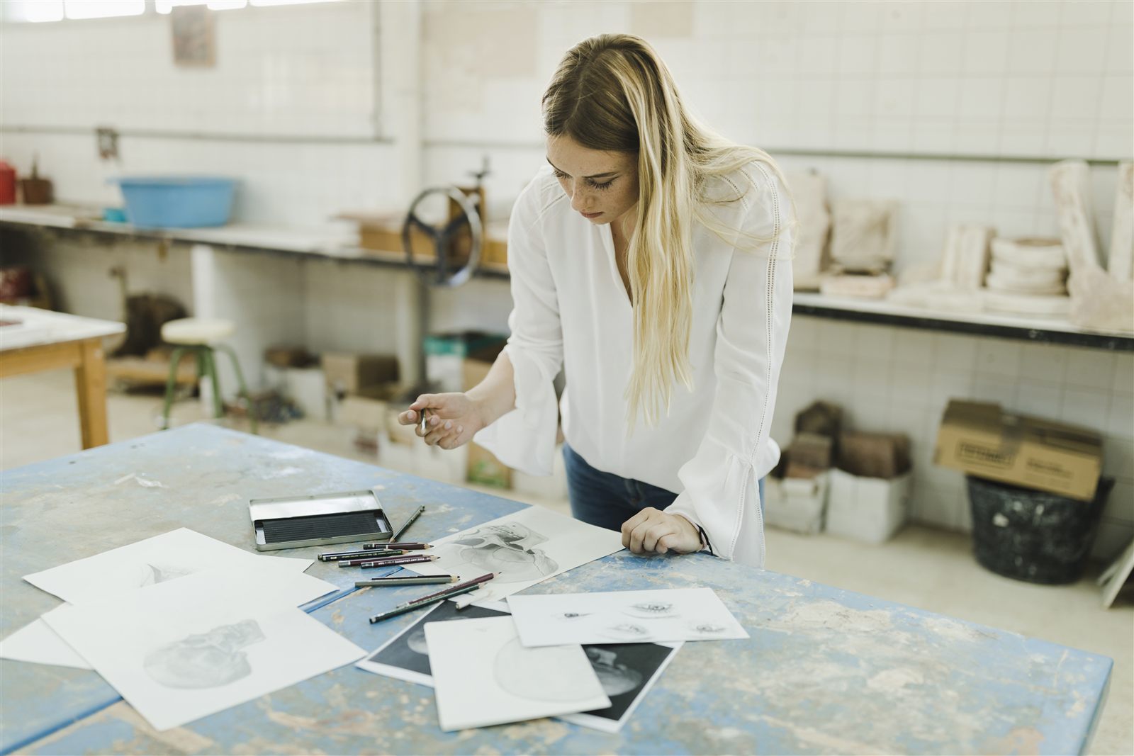 Diseñadora revisando bocetos y láminas sobre una mesa de un taller